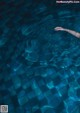 A person swimming in a pool with their hand in the water.