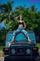 A woman sitting on top of a black jeep.