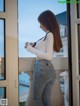 A woman standing on a balcony holding a camera.