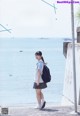 A woman in a school uniform standing next to the ocean.