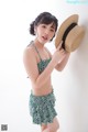 A woman in a bikini and a straw hat posing for a picture.