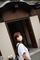 A woman standing in front of a building with a black bag.